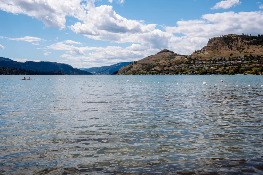 The calm waters of Kalamaka Lake bordered off into a designated swimming area by a string of white buoys with dry mountains in the distance