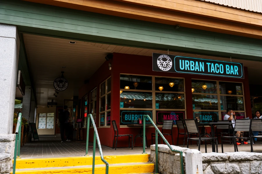 A large sign hangs in front of the windowed facade of La Cantina Tacos that reads ‘Urban Taco Bar’