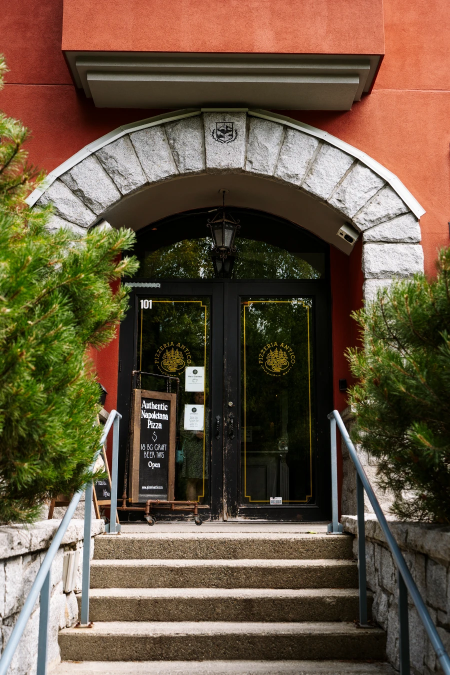 A large stone archway over the top of a rustic wooden doorway that leads into Pizzeria Antico