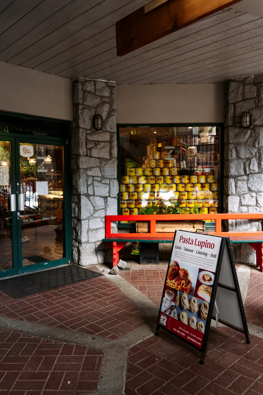 Dozens of canned tomatoes with yellow labels stacked in the window of Pasta Lupino in Whistler