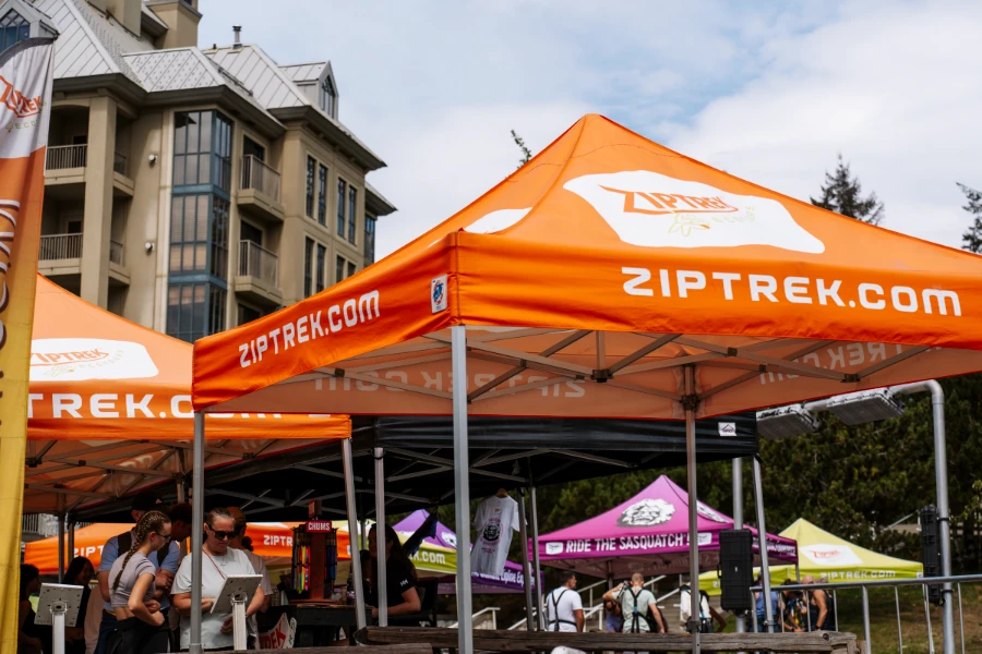 Several multicoloured tents set up outside at the base of the Whistler gondola, each with its own zip-lining company name printed on it