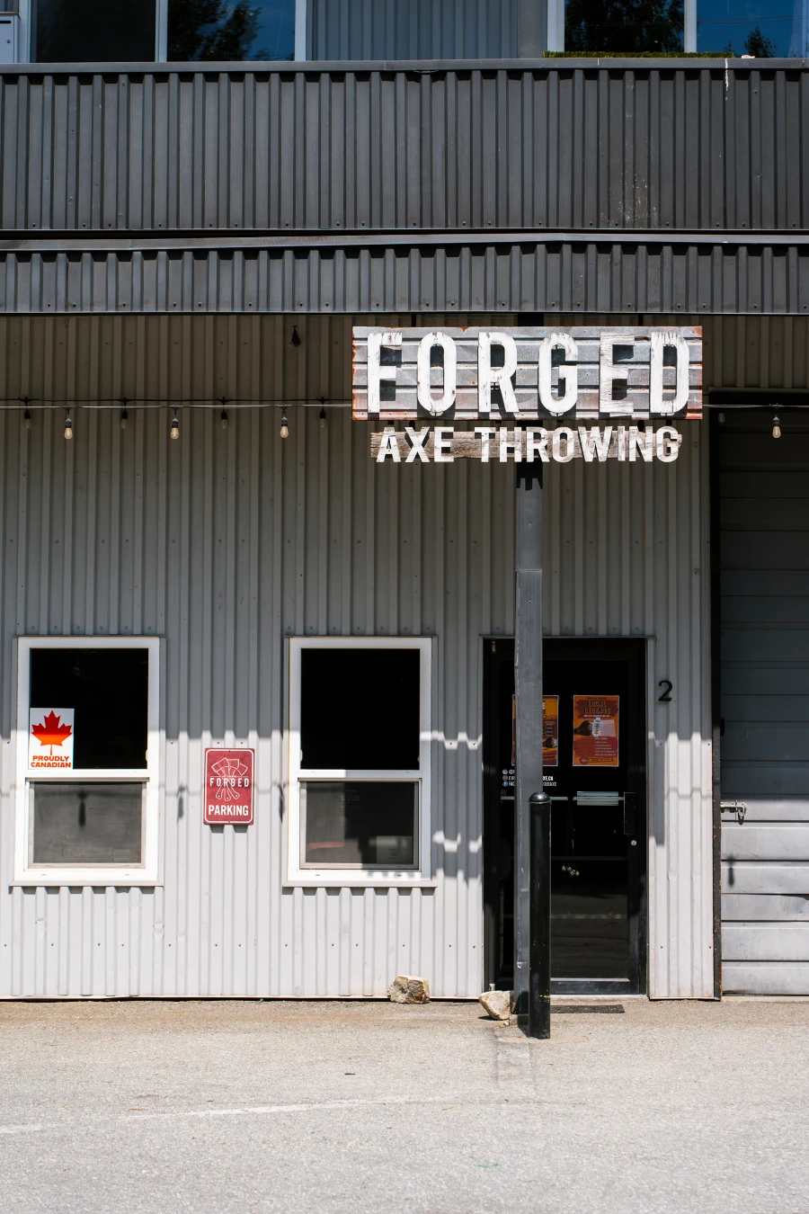 A large wooden sign outside of a wood-panelled building reads ‘Forged Axe Throwing’