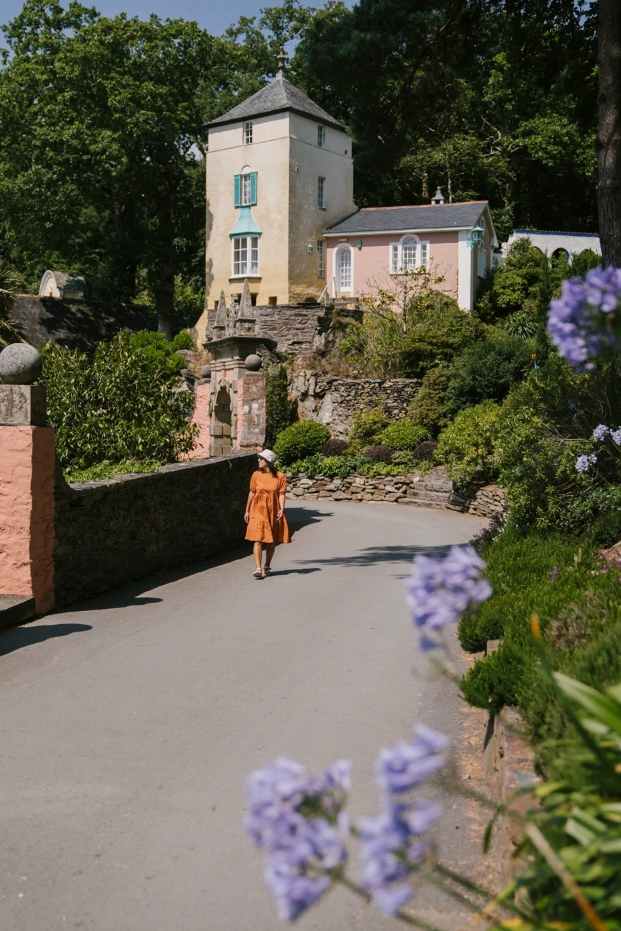 Woman walking along a paved road with pastel colored building behind her