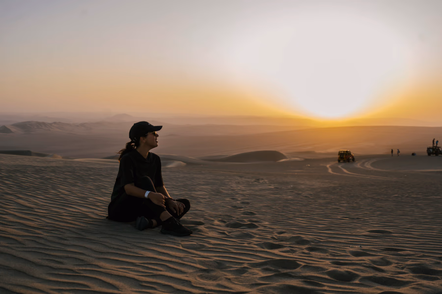 Best Things to Do In Huacachina, Peru: woman sits on the sands at sunset