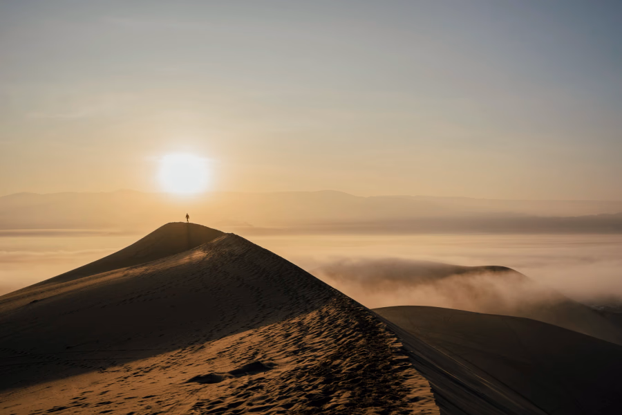 Best Things to Do In Huacachina, Peru: man stand atop a sand dune over a cloud inversion