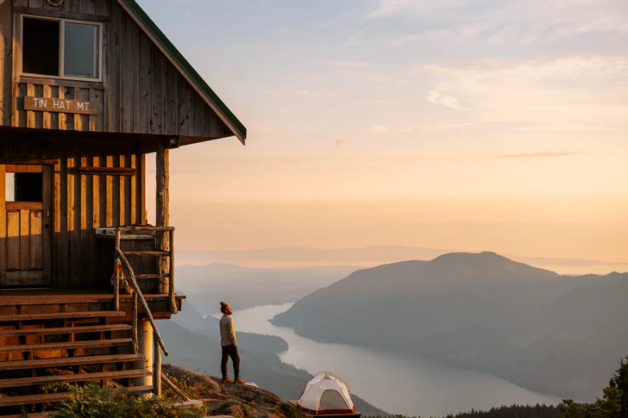 man stands next to a wooden hut this a ten set up below
