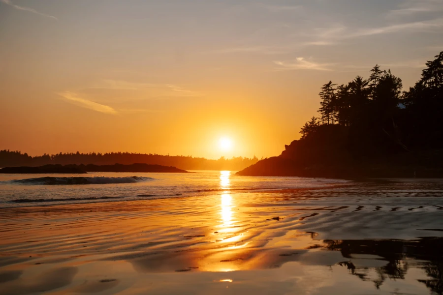 The wet sand of tin wis beach reflects the warm glow of the sunset