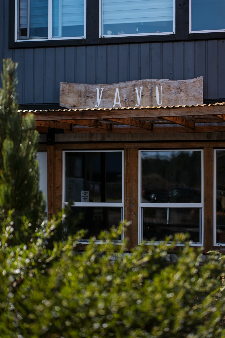 A cafe store front is framed by green bushes and the framed sign reads "Yayu"