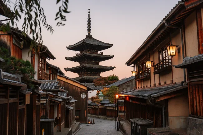 Empty streets lined by wooden shops lead to a large wooden Pagoda in Kyoto, Japan
