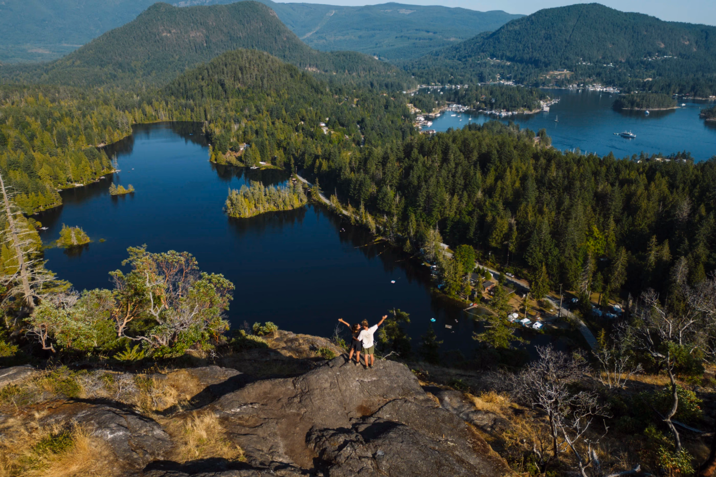 two people standing arm in arm at a viewpoint above a lake in Maderia Park, British Columbia