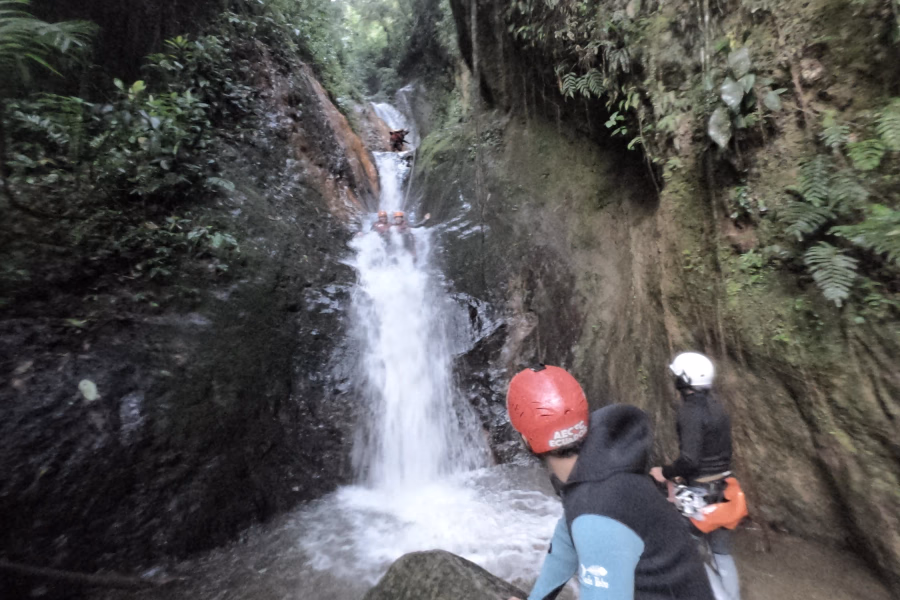 A group of tourists in wet suits and helmets climbing down waterfalls