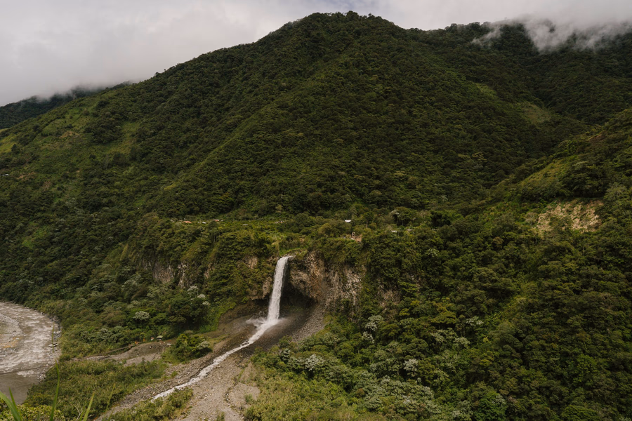 A powerful waterfall pours over a steep cliff before flowing into a river