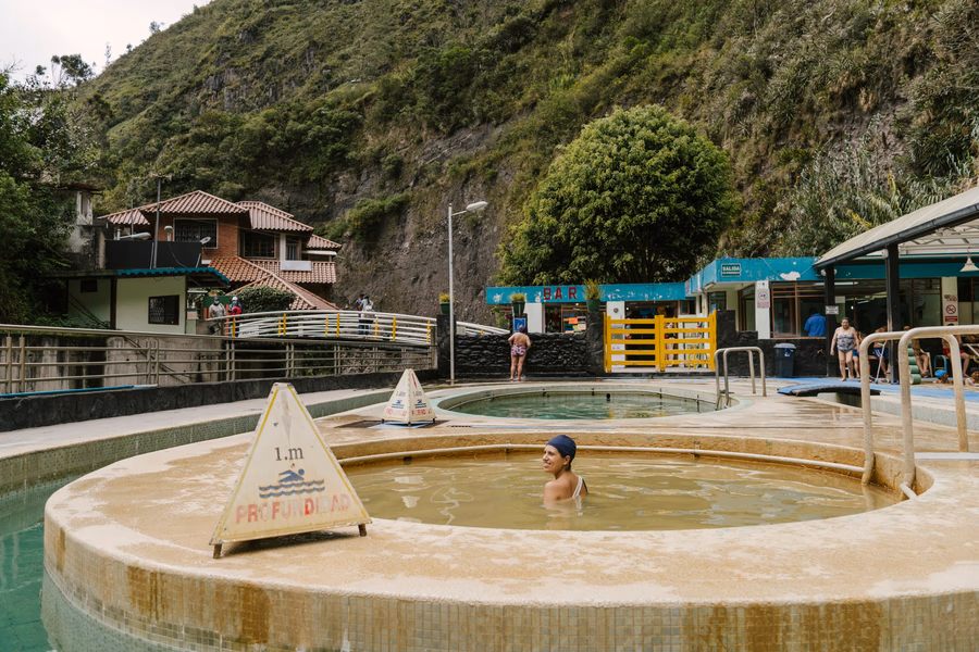 A woman wearing a plastic hair cap sits in the middle of a hot mineral pool at El Salado Thermal Baths
