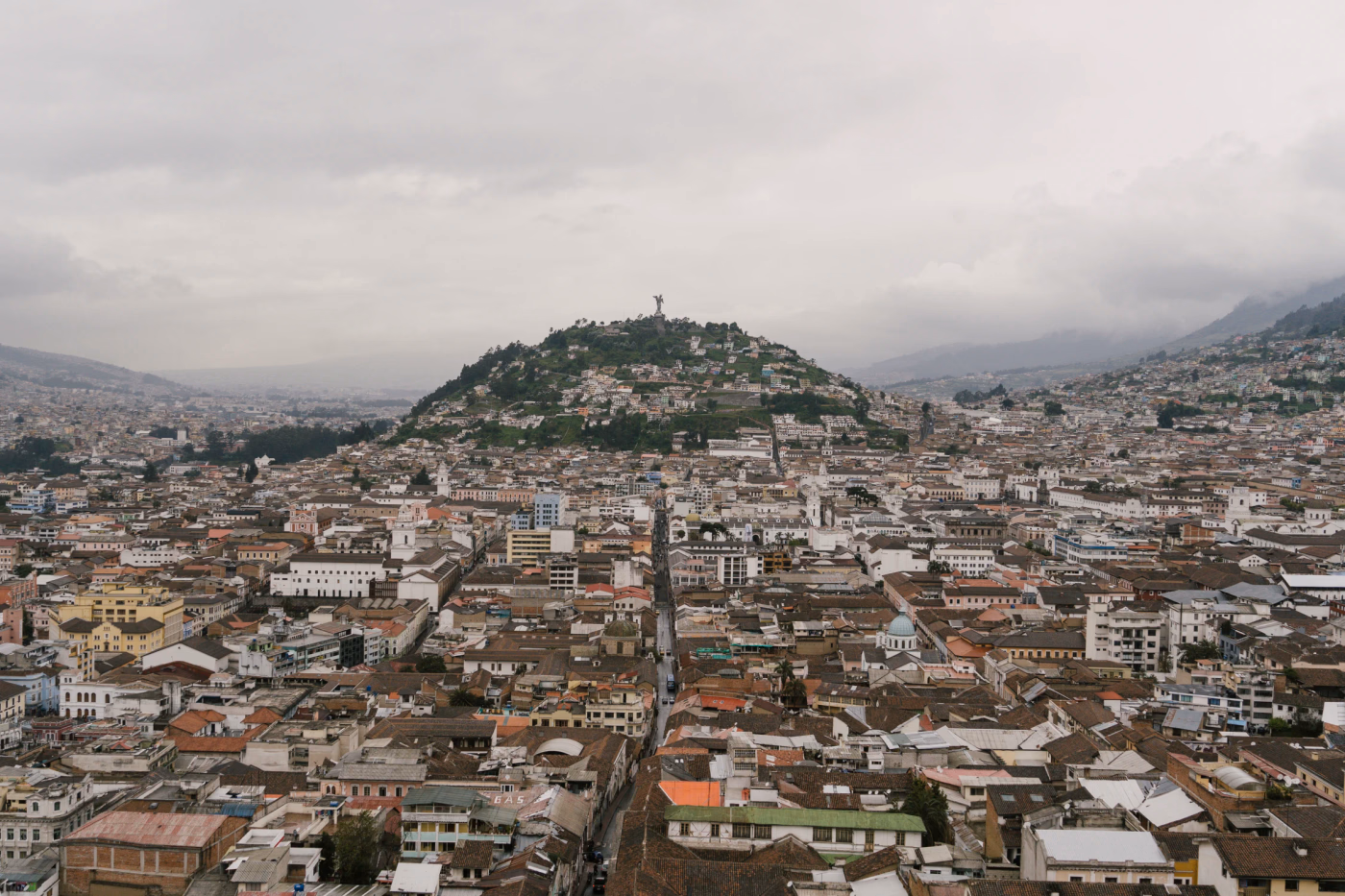 A sea of buildings surround a large hill in Quito, Ecuador