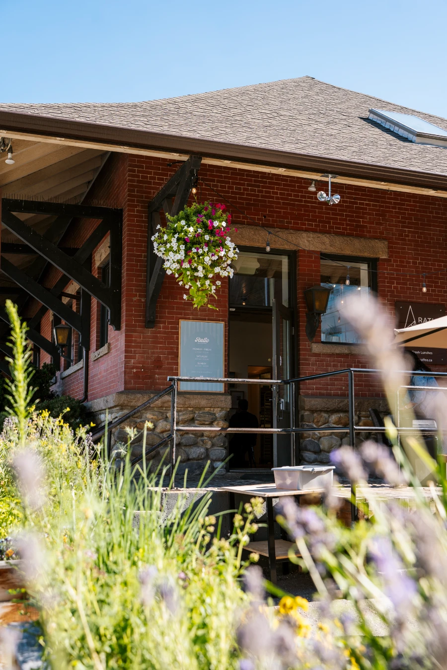 A flowerbed of lavender frames a one-story red brick building that houses Ratio Coffee & Bakery in Vernon
