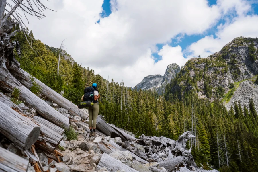 Woman with a large backpack standing in a clearing on trail to Watersprite Lake