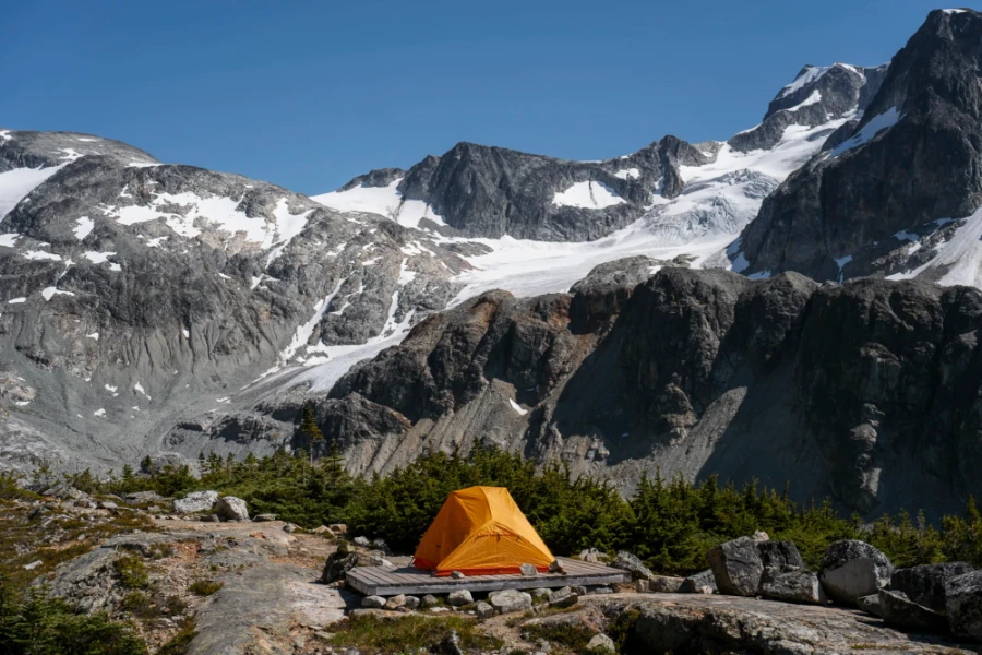 orange tent set up on a wooden tent pad at the Wedgemount Lake campsite