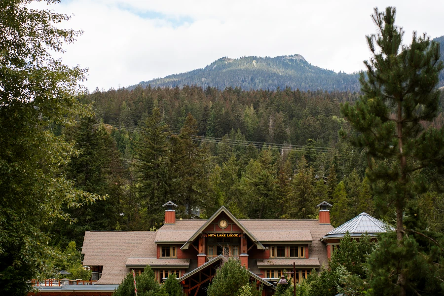 The front of Nita Lake Lodge sticking out above trees with a tree covered mountain behind it