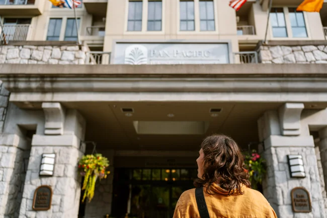 A woman standing in front of the entrance of the Pan Pacific hotel in Whistler