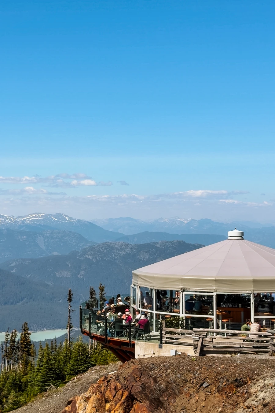 A crowd of people sitting at tables on the balcony of the Umbrella Bar on Whistler Mountain