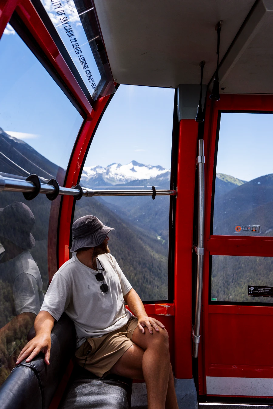 A man sitting in the red gondola car of the Peak 2 Peak gondola in Whistler