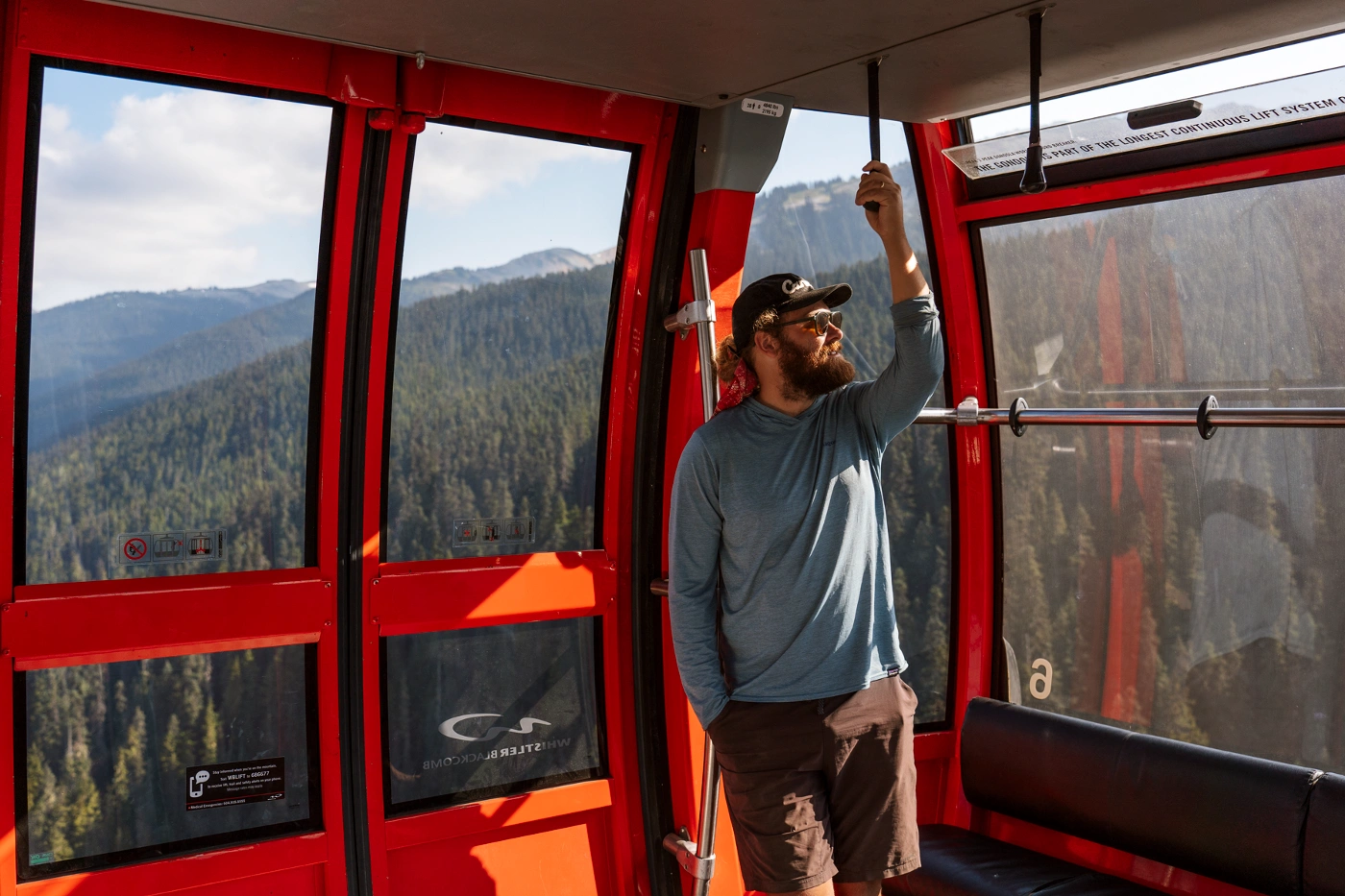 A man holds a strap for support while riding the Peak 2 Peak gondola in Whistler, BC