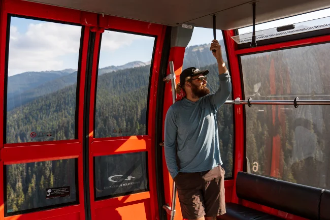 A man holds a strap for support while riding the Peak 2 Peak gondola in Whistler, BC